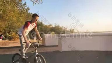 在阳光明媚的公园里，极端的BMX骑自行车和跳跃兔子跳跃技巧在夏天。 酷年轻的<strong>宝马</strong>骑车师做奥利奇